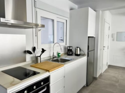 Cocina de apartamento de lujo frente al mar en Fuengirola con gabinetes blancos, electrodomésticos de acero inoxidable y vistas a la ciudad