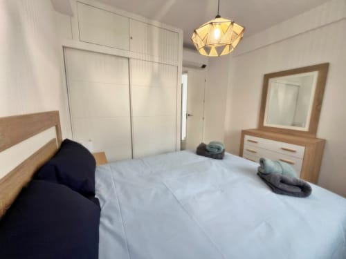 Dormitorio moderno frente al mar en Fuengirola con cama de madera, ropa de cama blanca y mobiliario contemporáneo