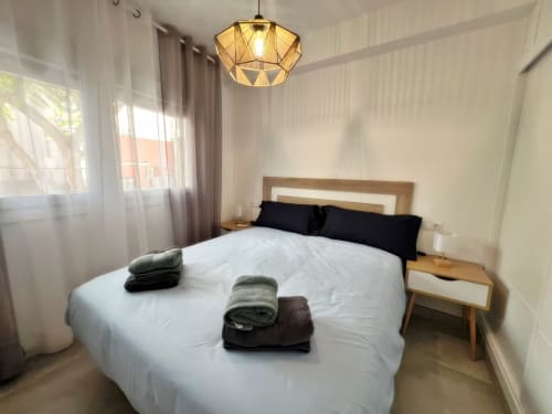 Moderno dormitorio en apartamento de lujo frente al mar en Grupo Inmo House, Fuengirola, con luminaria geométrica y vistas a la ciudad