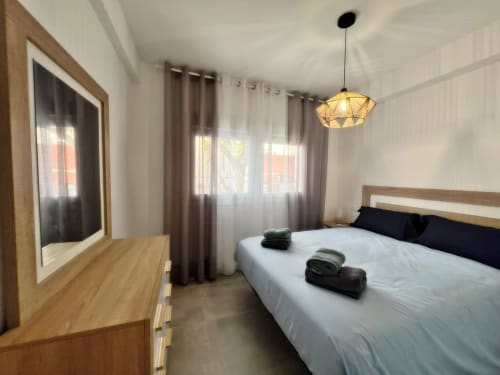 Apartamento de lujo en primera línea de playa en Fuengirola con cama queen, muebles de madera, iluminación moderna y vistas a la ciudad