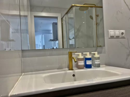 Elegante lavabo de baño con grifo de latón y artículos de tocador en lujoso apartamento de playa en Fuengirola por Grupo Inmo House
