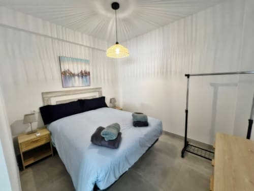 Dormitorio de apartamento de lujo frente al mar en Fuengirola con mobiliario moderno e iluminación colgante amarilla