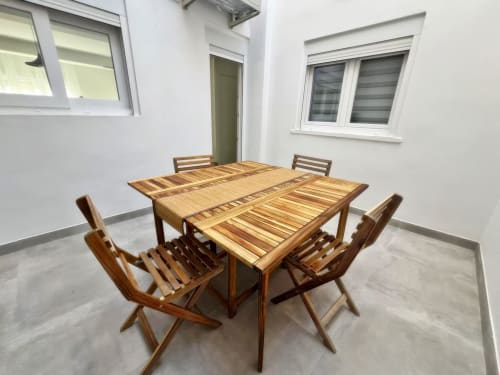 Mesa de comedor de madera con cuatro sillas en luminoso apartamento de Fuengirola con grandes ventanales y comodidades modernas