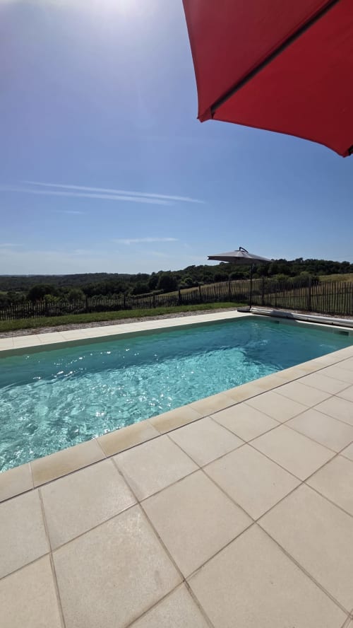 Rode parasol die een onberispelijk zwembad met turquoise water van Home Sweet Lodge Glamping Aquitaine beschadukt
