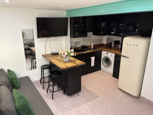 Cuisine et salon duplex modernes dans un appartement du Marais à Paris avec réfrigérateur SMEG crème, plan de travail en bois et électroménagers noirs.