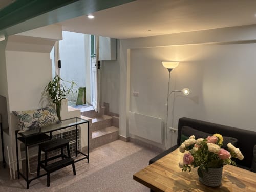 Modern Duplex Marais apartment in Paris with open living area, wood dining table with flowers, black furniture, and access to