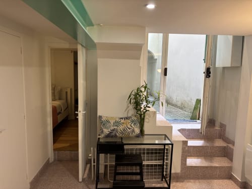 Modern Marais apartment entryway with stairs, seating area, and glass doors opening to patio near Pompidou
