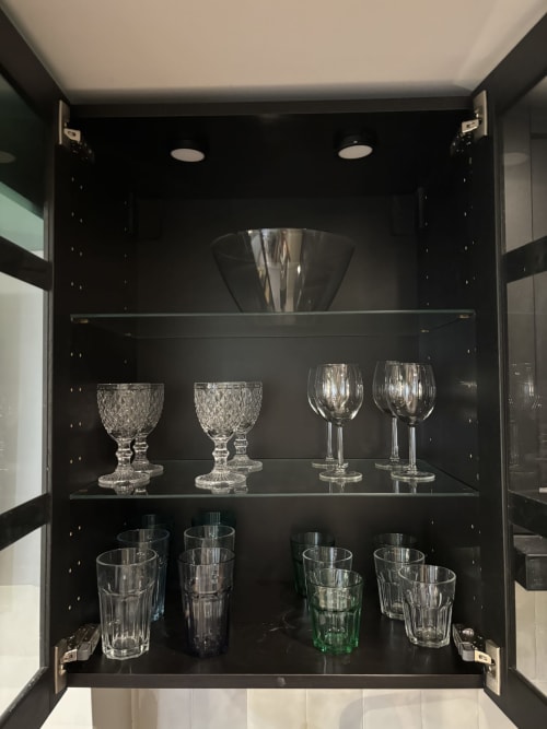 Black glassware cabinet displaying elegant crystal stemware and glasses in Aldaro's Duplex Marais apartment, Paris