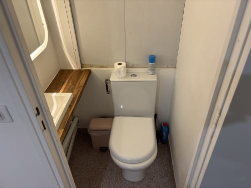 Compact toilet bathroom in Aldaro Paris apartment with white toilet, sink, and wood countertop near Pompidou