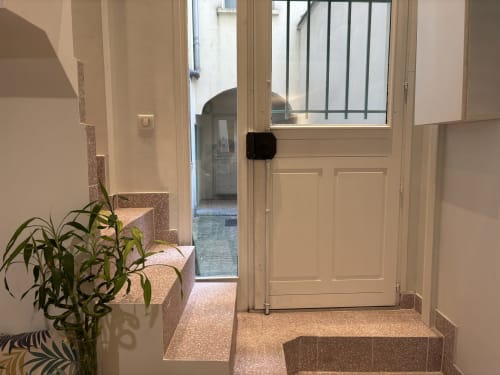 Bright modern entryway of Paris Duplex apartment with cream doors, potted plant, and tiled floor near Pompidou