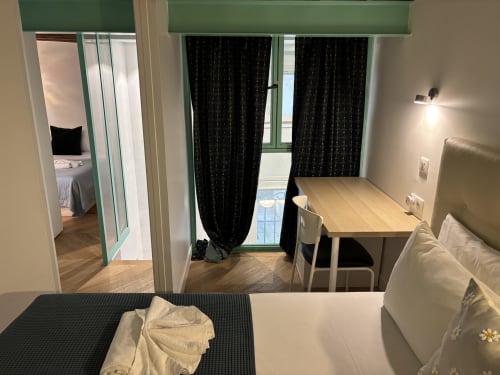 Duplex Marais apartment in Paris with bedroom, desk workspace, and balcony with black curtains overlooking city