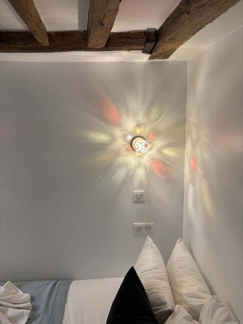 Bedroom ceiling with exposed wooden beams and decorative light fixture casting colorful light, Duplex Marais Paris