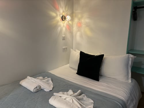 Modern bedroom at ALDARO Duplex Marais in Paris with bed, white pillows, black accent pillow, and wall-mounted lighting