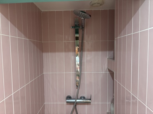 Modern bathroom shower at ALDARO Duplex Marais apartment in Paris with pink tiled walls and rainfall showerhead