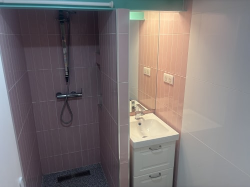 Modern bathroom in Duplex Marais apartment with purple tiled shower, white sink vanity, and pink tiled walls at ALDARO Paris