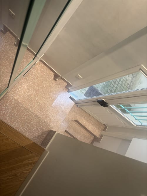 Bright Duplex Marais apartment interior with wooden floors, beige carpet stairs, skylight, and white ceiling in Paris