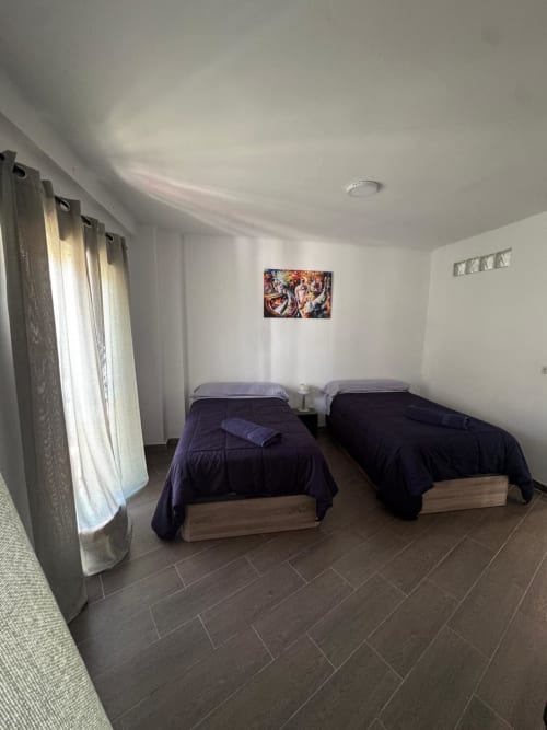 Habitación doble con ropa de cama azul oscuro y marcos de madera en el apartamento Torre Sol Y Playa en Torremolinos, España
