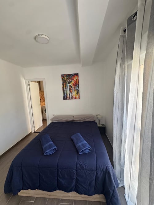 Dormitorio moderno del apartamento Torre Sol Y Playa en Torremolinos con cama azul marino y toallas enrolladas