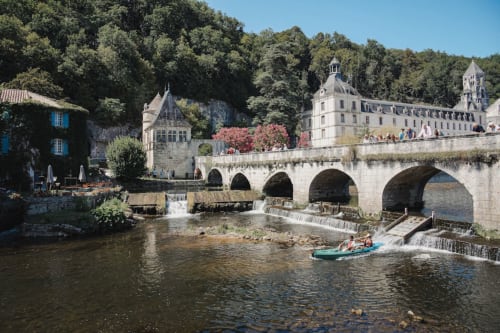 Pont de pierre médiéval surplombant la rivière avec château et jardins du Domaine de Châlus-Chabrol à Châlus, France