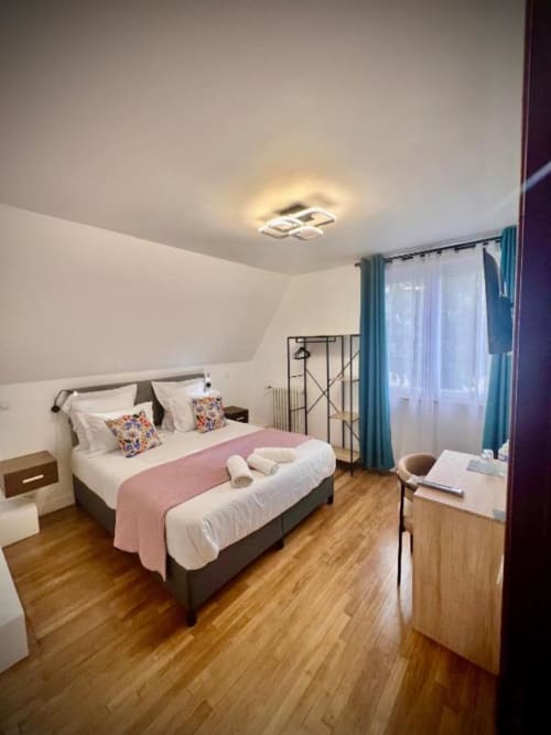 Chambre deluxe avec lit king à La Villa Cassinne, sols en bois, rideaux turquoise et vue sur le jardin