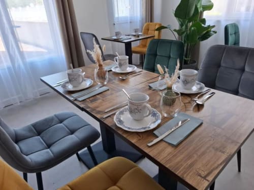 Élégante salle à manger à La Villa Cassinne avec table dressée, chaises capitonnées, vue sur le jardin et équipements modernes accessibles