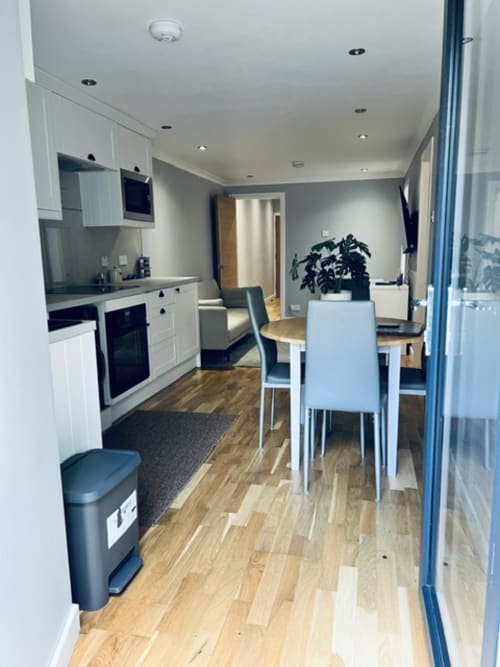 Modern open-plan kitchen and dining area in Whiteleys Cottages cottage, featuring white cabinetry, dining table, and wooden