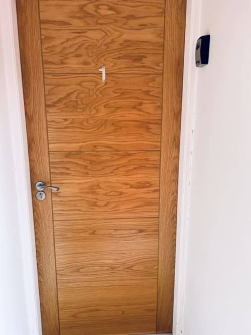 Wooden door with horizontal paneling and metal handle at Whiteley's Cottages cottage in Dumbarton