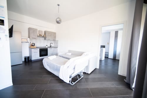 Argiro Deluxe Apartment a Newhouse Bari - monolocale moderno con cucina, letto, divano e pavimenti scuri