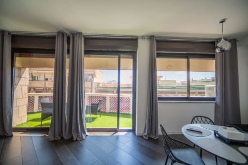 Appartamento Argiro Deluxe a Bari con porte scorrevoli in vetro che si aprono sul balcone arredato, tende grigie e pavimento in piastrelle scure