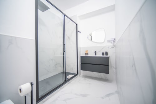 Bagno moderno nell'appartamento Newhouse Argiro Deluxe a Bari con piastrelle in marmo, mobile scuro e cabina doccia in vetro