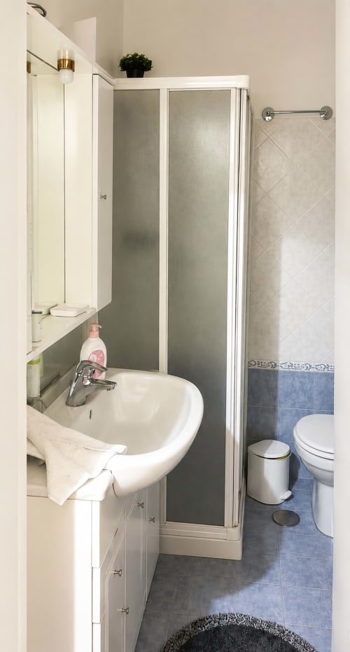 Compact bathroom with pedestal sink, shower enclosure, and toilet in Roma apartment
