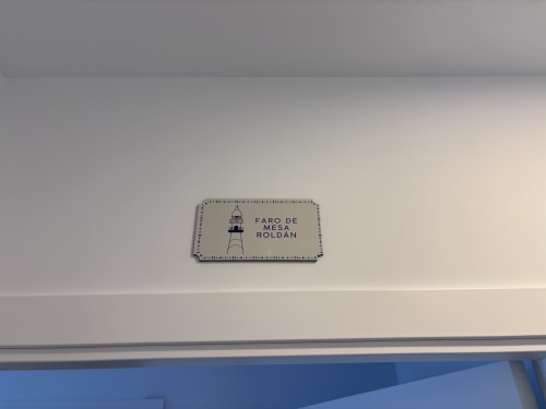 Decorative plaque reading 'Faro de Mesa Roldan' with lighthouse illustration on hotel room wall