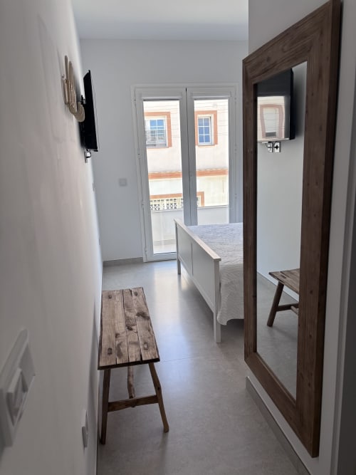 Modern bedroom with sea view balcony at La Llar B&B, Carboneras. Double bed, wooden furniture, flat-screen TV, and glass