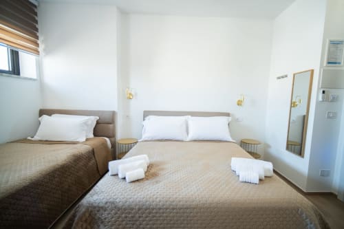 Camera luminosa dell'hotel Newhouse Bari con due letti, cuscini bianchi, asciugamani piegati e finestra con vista città