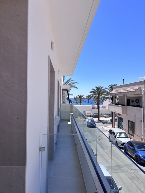 Balcony view from El Faro room at La Llar in Carboneras with sea view, palm trees, and parked cars below