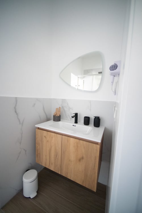 Bagno moderno a Newhouse Bari con vanity in legno, lavabo bianco, specchio a goccia e pavimento scuro