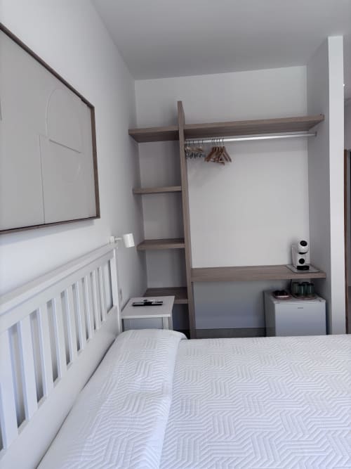 Moderna habitación doble en La Llar B&B de Carboneras con cama blanca, armario de madera oscura, estanterías y decoración minimalista