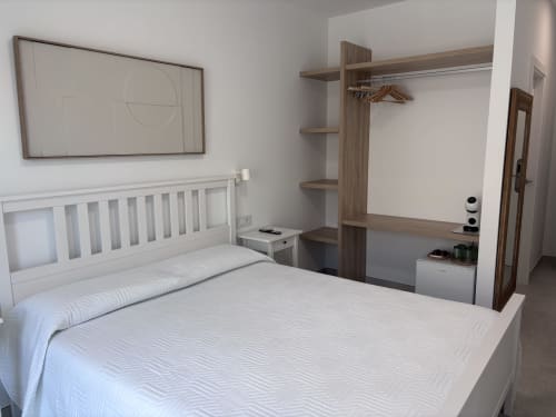Moderna habitación doble en La Llar, Carboneras con cama blanca, armario de madera y balcón con vistas al mar