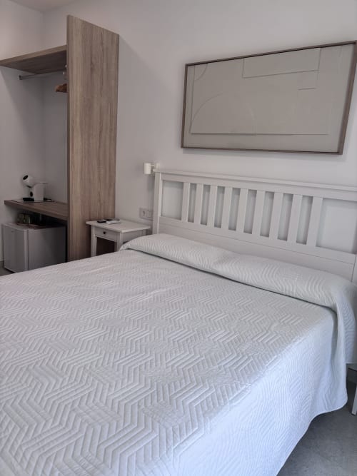 Modern double bedroom at La Llar Carboneras with white bed, wooden partition, flat-screen TV, and sea view window