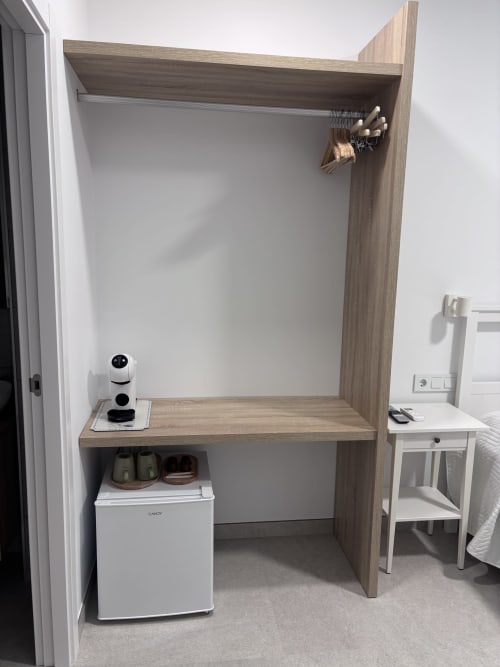 Wooden wardrobe closet with hanging rail, mirror, shelf, and mini fridge in La Llar room