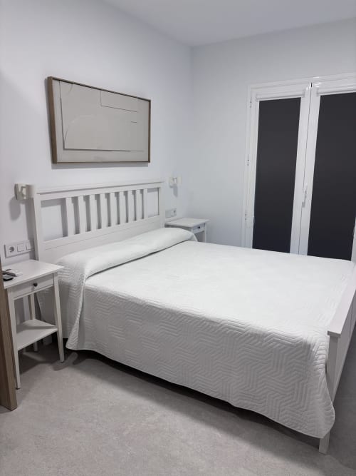 Modern double bedroom at La Llar boutique hotel in Carboneras with white bed, flat-screen TV, and sea views
