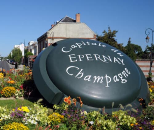 Géante sculpture de bouteille de champagne à la Demeure De La Garenne à Montmirail, entourée de fleurs colorées