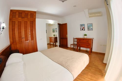 Espacioso dormitorio en Apartamentos La Palmera con camas gemelas, armario de madera, cómoda y vistas al mar en La Frontera