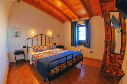 Bright bedroom at Casa La Tabona cottage with colorful bedding, wooden beams, and sea views at Apartamentos La Palmera, La