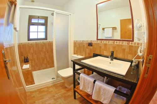 Modern bathroom in Casa La Tabona cottage with walk-in shower, double sink vanity, and terracotta tile flooring at La Palmera