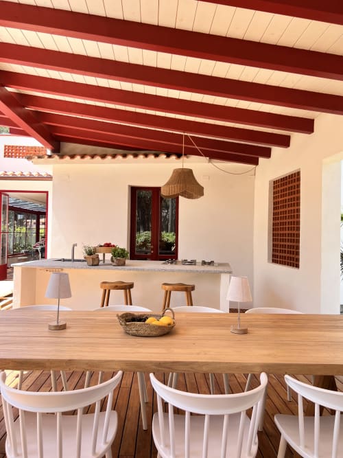 Spacious outdoor dining and kitchen area at Casa Pineta villa in Marina di Campo with wooden table, white chairs, and red