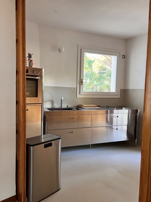 Modern kitchen with stainless steel appliances and sink at Casa Pineta villa, Marina di Campo, with window overlooking palm