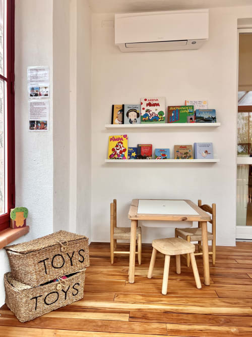 Kids playroom at Casa Pineta villa with wooden table, toys, books, and storage baskets on hardwood floor