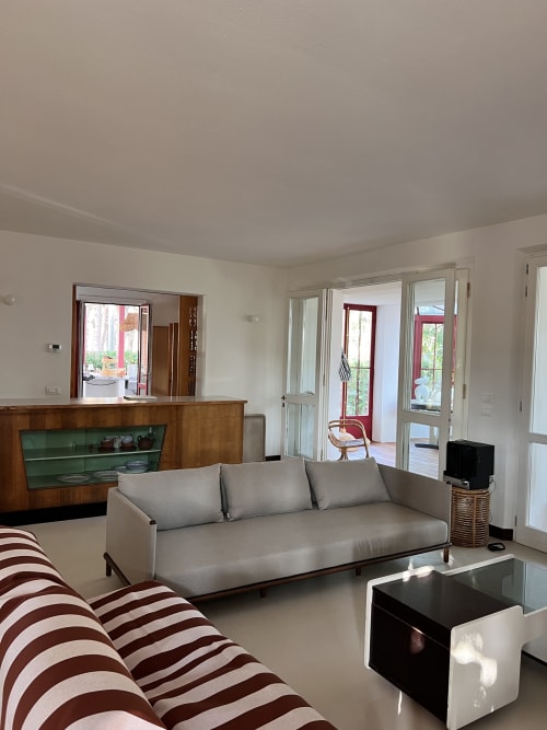 Bright living room in Casa Rossa villa at Casa Pineta, Marina di Campo, with gray sofa, striped armchair, and sea view
