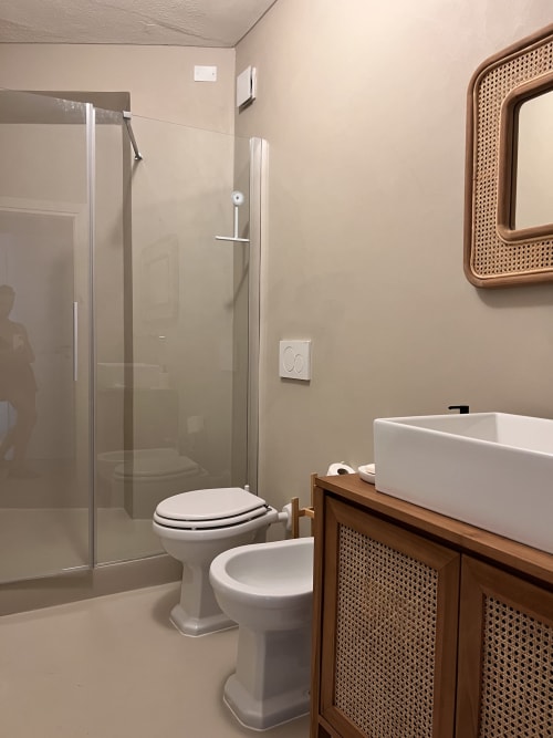 Modern bathroom at Casa Rossa villa in Marina di Campo with white toilet, bidet, vessel sink, and glass shower enclosure